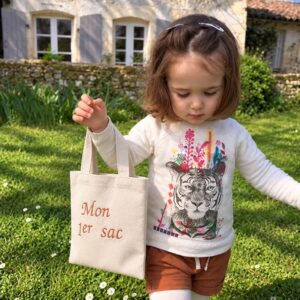 Petite fille portant un tote bag enfant beige personnalisé par broderie